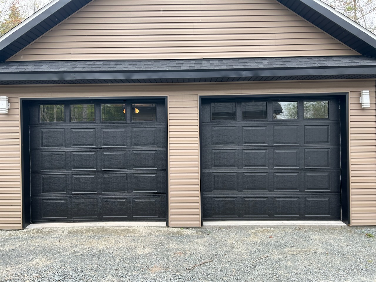 Two black garage doors on a beige garage
